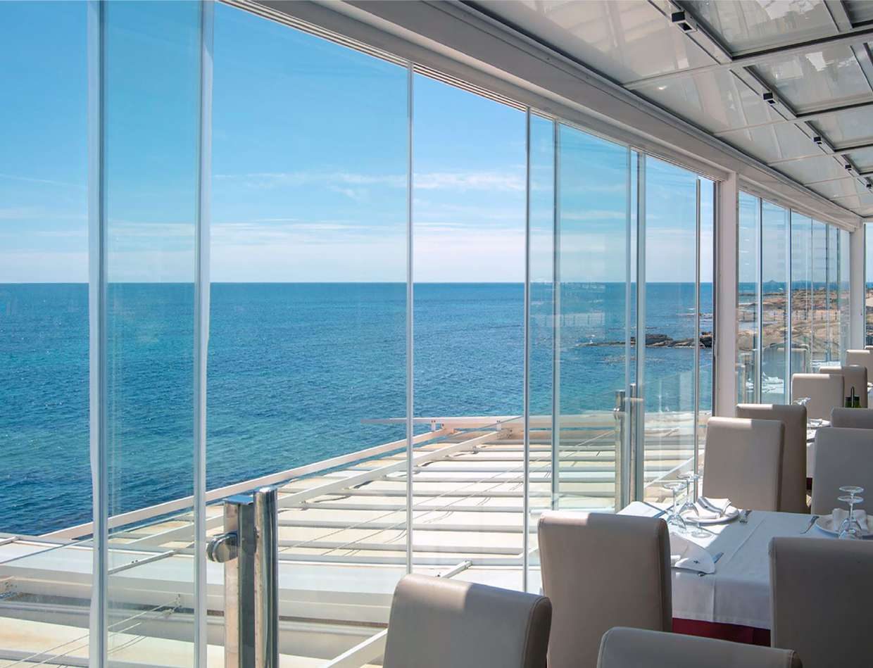 Comedor de un restaurante frente al mar cerrado con correderas de cristal